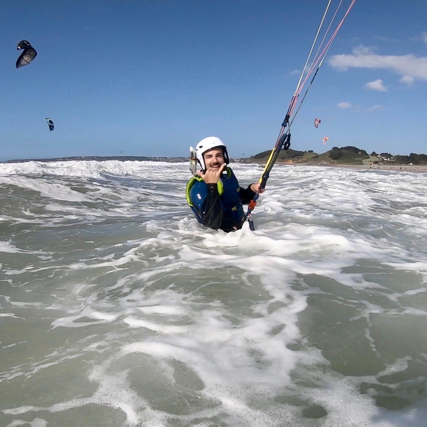 kitesurfeurs dans la mer faisant un geste de sympathie avec sa main