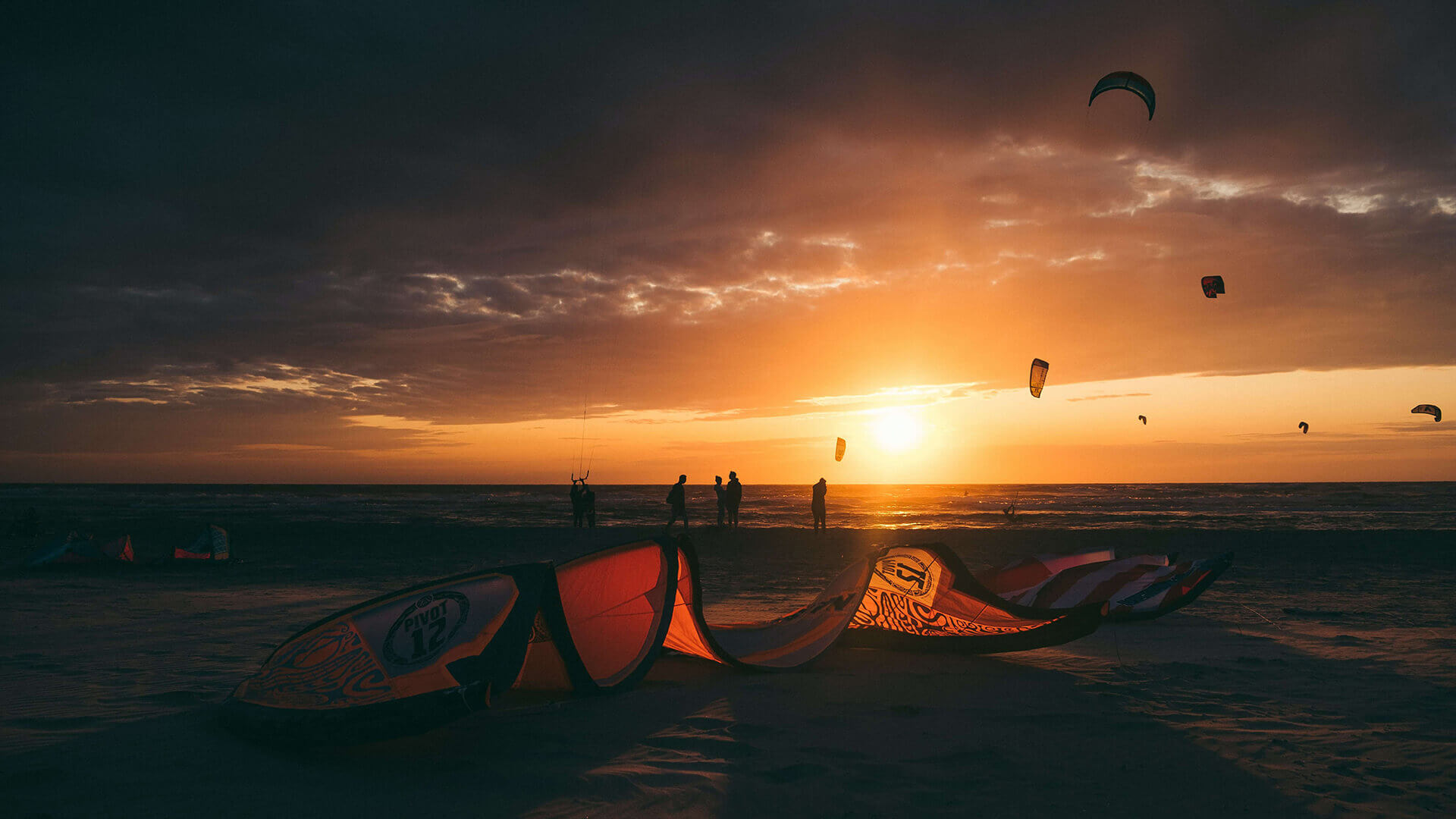 Couché de soleil avec des kitesurfeurs au bord de la mer